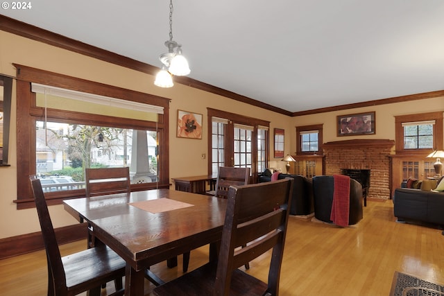 dining area featuring ornamental molding, light wood-type flooring, and a fireplace