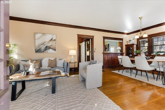 living room with crown molding, wood-type flooring, and a notable chandelier