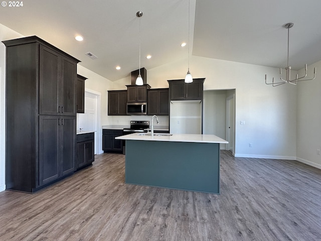 kitchen featuring refrigerator, sink, decorative light fixtures, and a center island with sink