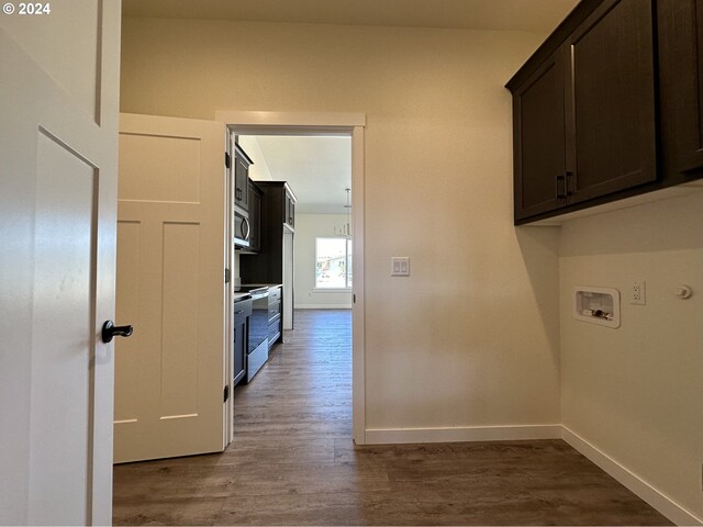 clothes washing area with hardwood / wood-style floors, hookup for a washing machine, and cabinets