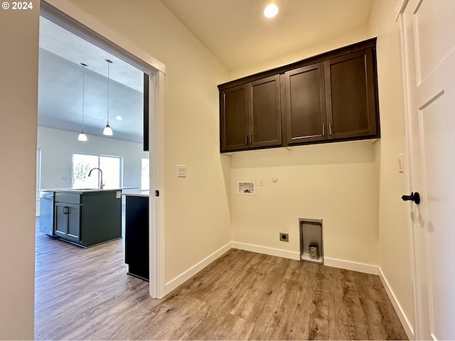 clothes washing area with sink, hookup for a washing machine, cabinets, hookup for an electric dryer, and light wood-type flooring