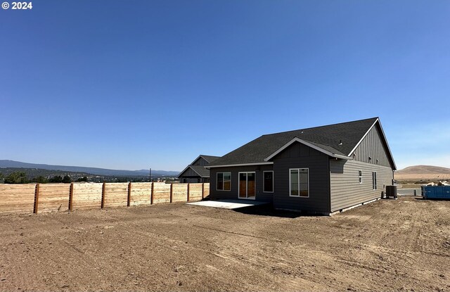 rear view of house featuring central AC, a mountain view, a patio, and a rural view