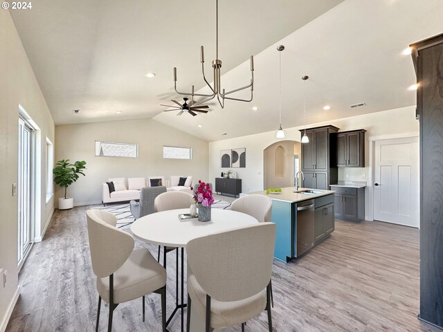 dining space with ceiling fan with notable chandelier, lofted ceiling, sink, and light wood-type flooring