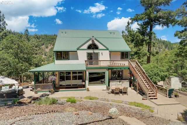 back of property featuring stairway, a patio, a view of trees, and metal roof