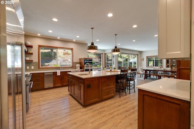 kitchen with a kitchen island with sink, a sink, recessed lighting, stainless steel appliances, and light wood finished floors