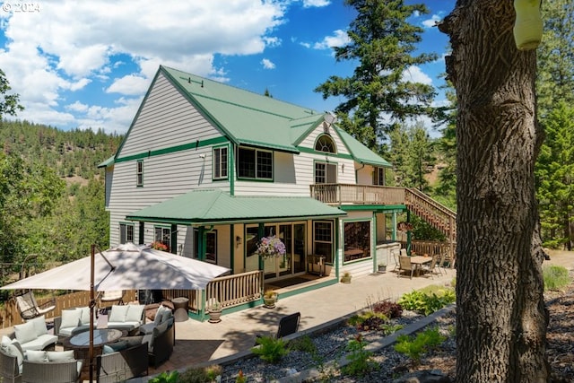 back of property with metal roof, an outdoor hangout area, covered porch, and a patio