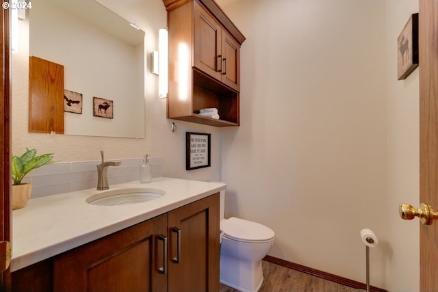 bathroom with baseboards, toilet, wood finished floors, and vanity