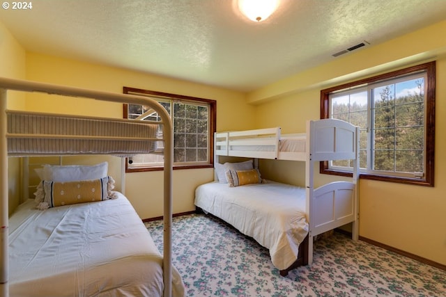 bedroom with a textured ceiling, carpet, visible vents, and baseboards