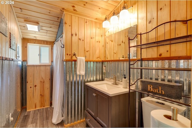 full bathroom with toilet, wood finished floors, wood walls, wooden ceiling, and vanity