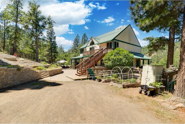 view of front of house with stairway, metal roof, and a garden