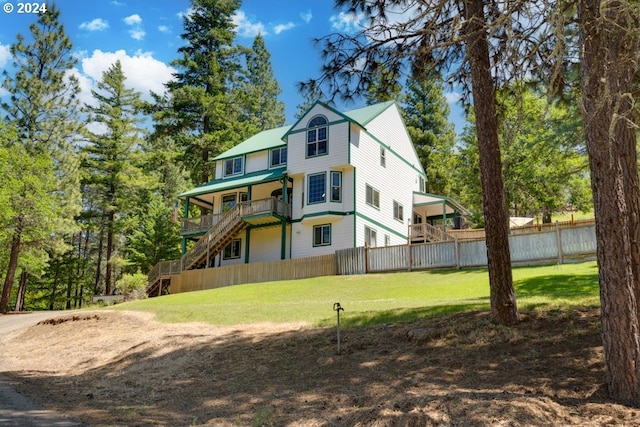 rear view of property with a lawn, stairs, and fence