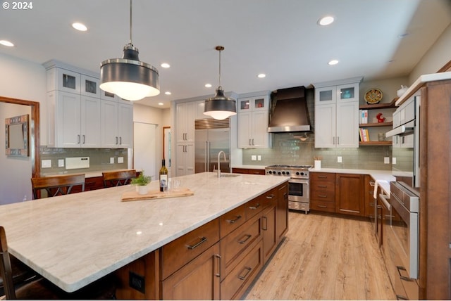 kitchen with open shelves, light wood-style flooring, recessed lighting, wall chimney exhaust hood, and premium appliances