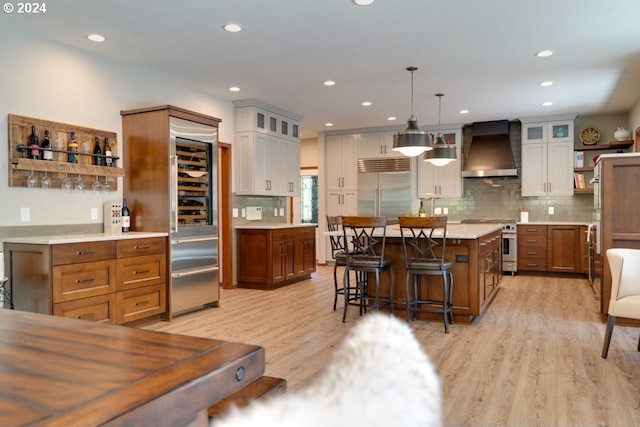 kitchen featuring open shelves, light wood-style flooring, a kitchen breakfast bar, wall chimney range hood, and high quality appliances