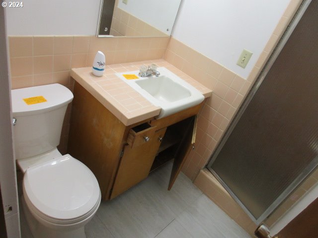 bathroom with tile patterned floors, vanity, tile walls, and toilet