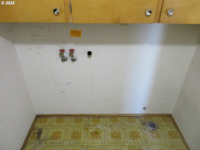 clothes washing area with cabinets and tile patterned floors