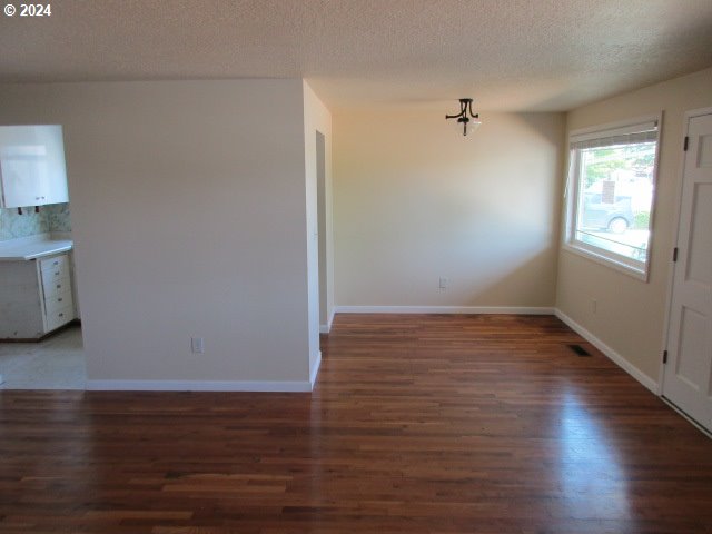 empty room with hardwood / wood-style floors and a textured ceiling