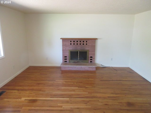 unfurnished living room featuring a fireplace, wood-type flooring, and a textured ceiling