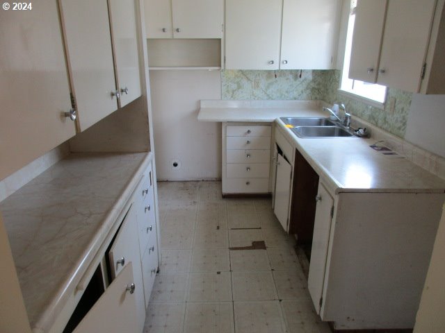 kitchen featuring sink, white cabinetry, backsplash, and light tile patterned floors