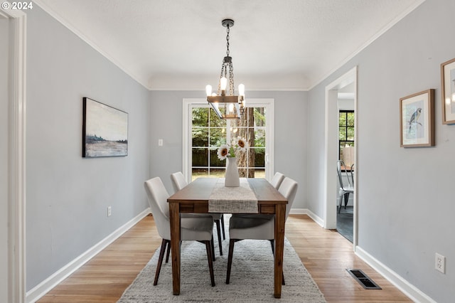 dining area with a chandelier, light hardwood / wood-style floors, and crown molding