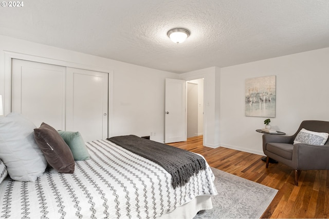 bedroom with a closet, wood-type flooring, and a textured ceiling