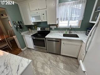 kitchen with light stone counters, white cabinetry, sink, and appliances with stainless steel finishes