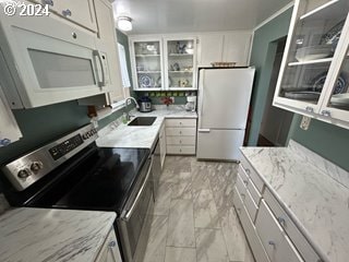 kitchen with light stone countertops, white appliances, white cabinetry, and sink