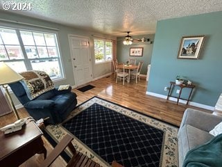 living room featuring hardwood / wood-style flooring, ceiling fan, and a textured ceiling