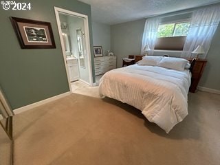 bedroom with connected bathroom and light colored carpet