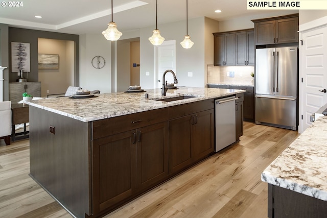 kitchen with dark brown cabinetry, stainless steel appliances, light stone counters, and sink