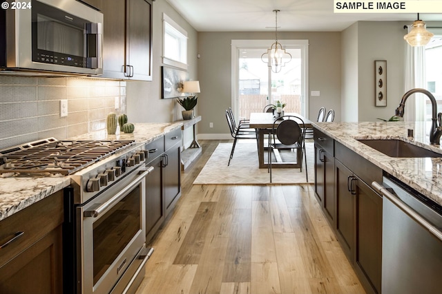 kitchen with sink, decorative light fixtures, light hardwood / wood-style flooring, dark brown cabinets, and stainless steel appliances