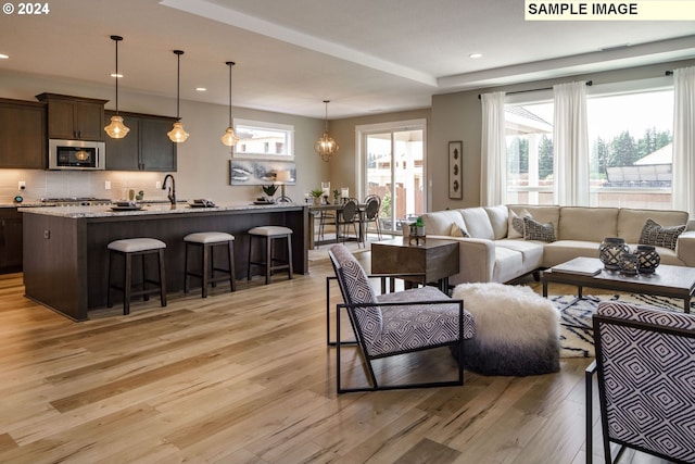 living room with light hardwood / wood-style floors, sink, and an inviting chandelier