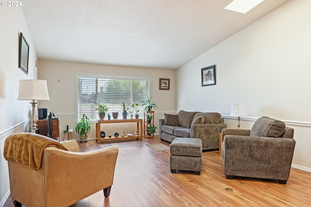 living room with wood-type flooring and vaulted ceiling with skylight