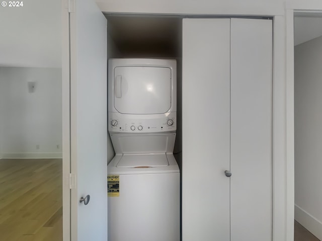 laundry area featuring hardwood / wood-style floors and stacked washer and clothes dryer