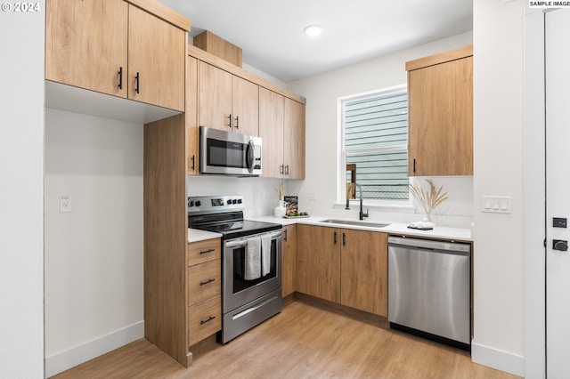 kitchen with stainless steel appliances, light hardwood / wood-style floors, light brown cabinets, and sink