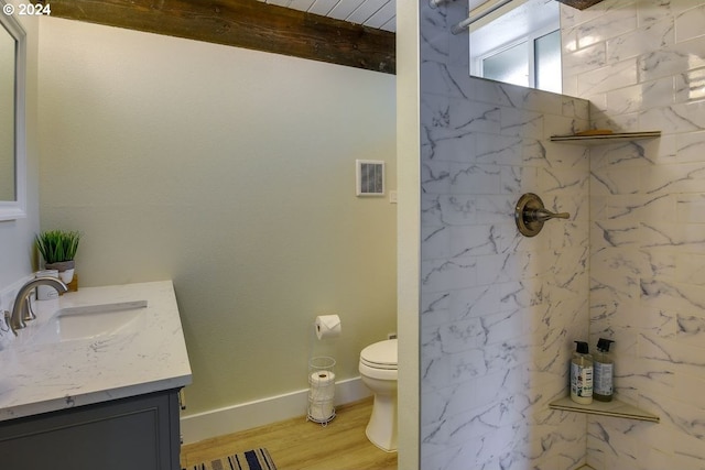 bathroom featuring hardwood / wood-style flooring, vanity, toilet, and a tile shower