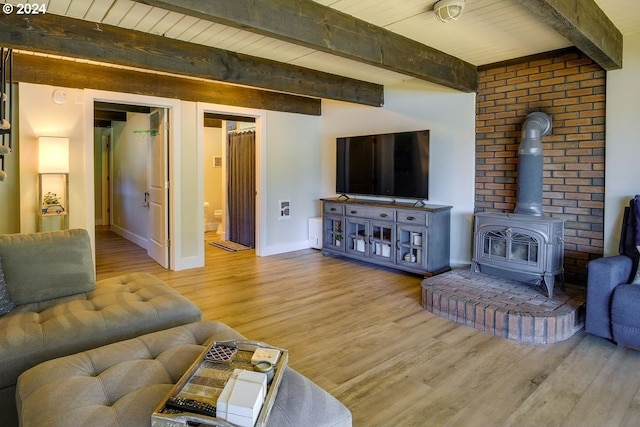 living room featuring beam ceiling, wood-type flooring, and a wood stove