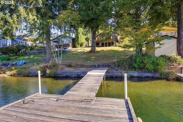 dock area with a lawn and a water view