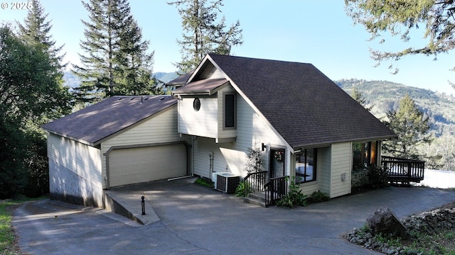 17265 Mountain Dr, Brookings, OR 97415 - view of front of home featuring roof with shingles, a mountain view, cooling unit, driveway, and an attached garage