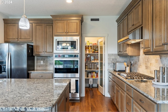 kitchen featuring stainless steel appliances, light stone countertops, a textured ceiling, and dark hardwood / wood-style floors