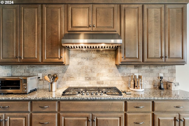 kitchen featuring stainless steel gas stovetop, light stone countertops, and tasteful backsplash