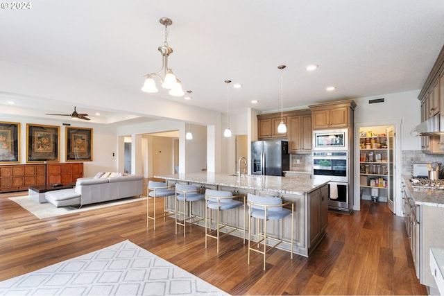 kitchen featuring backsplash, appliances with stainless steel finishes, dark hardwood / wood-style floors, and hanging light fixtures