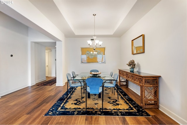 dining room featuring a notable chandelier, a tray ceiling, and dark hardwood / wood-style flooring