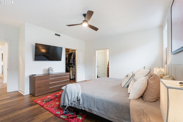 bedroom with a spacious closet, ceiling fan, a closet, and dark hardwood / wood-style floors