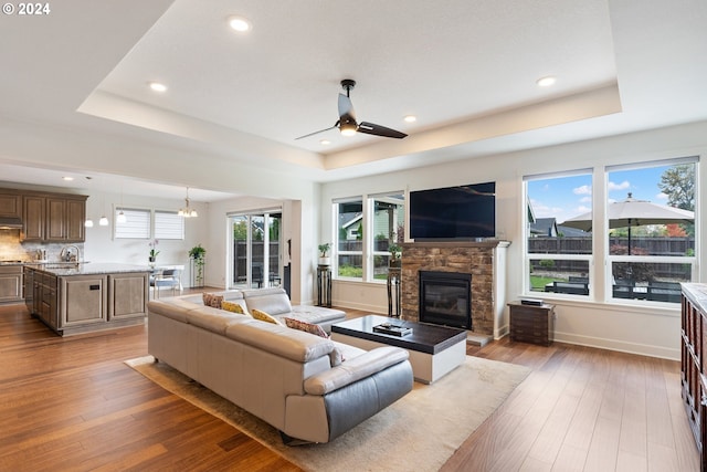 living room featuring hardwood / wood-style floors, a healthy amount of sunlight, sink, and a raised ceiling