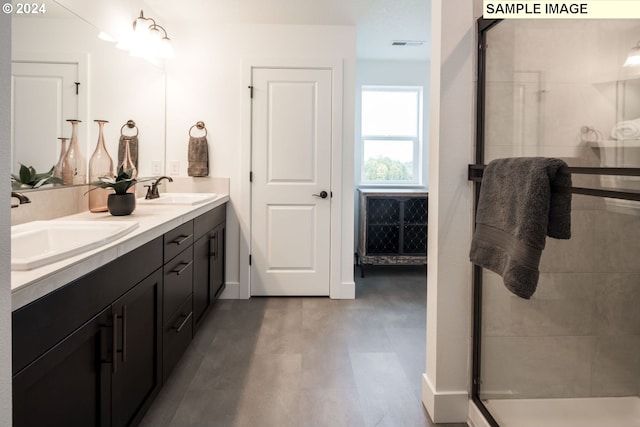 bathroom featuring a stall shower, visible vents, a sink, and double vanity