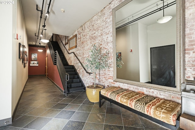 hall with track lighting and brick wall