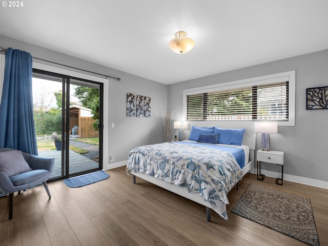 bedroom featuring access to exterior, wood-type flooring, and multiple windows