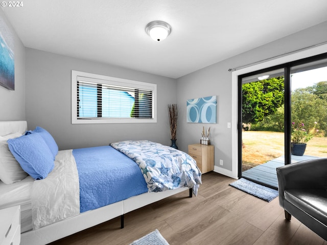 bedroom with access to exterior, light hardwood / wood-style flooring, and multiple windows