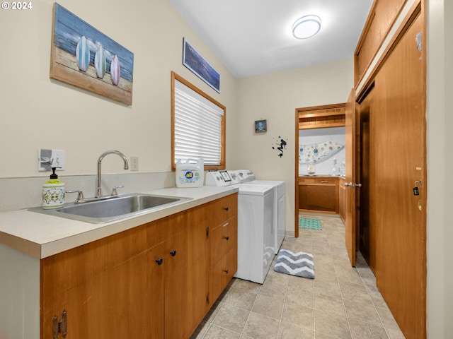 laundry room featuring separate washer and dryer, sink, light tile patterned floors, and cabinets