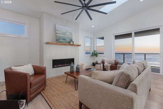 living room featuring light hardwood / wood-style floors, a water view, a healthy amount of sunlight, and a fireplace